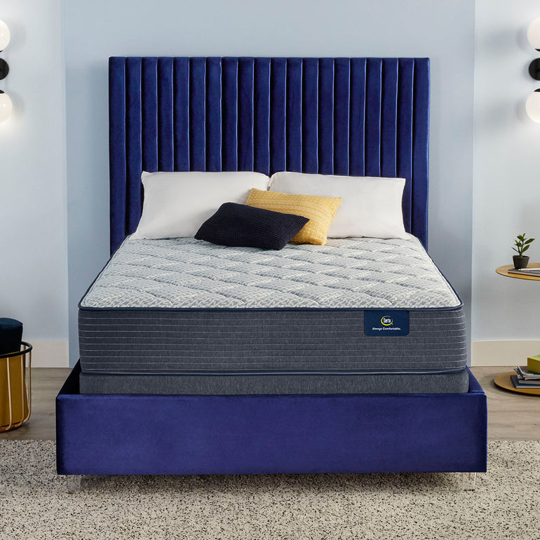Serta mattress with pillows on top of it and sitting on a blue bed frame