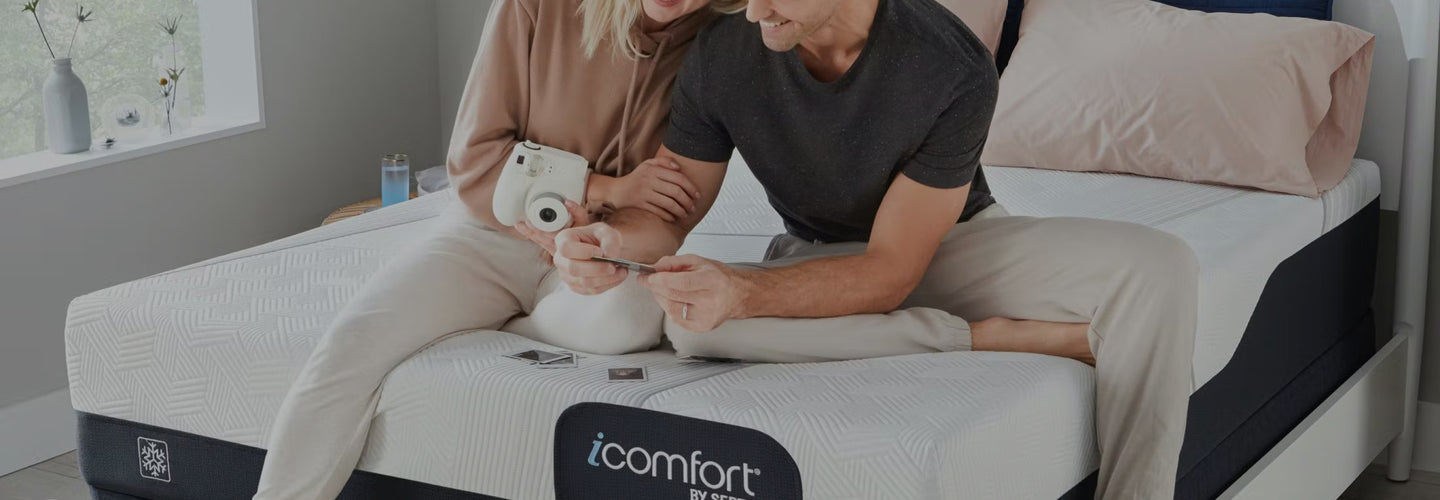 A couple sitting on Serta icomfort mattress looking at pictures